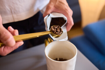 Pouring freshly ground coffee beans into a measuring cup for a perfect morning brew