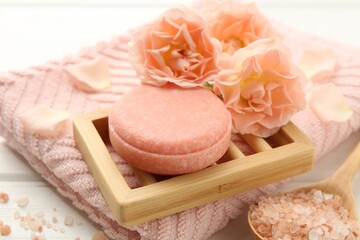 Soap bar, sea salt and beautiful flowers on white wooden table, closeup
