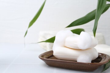 Soap bars with foam on white table, closeup. Space for text