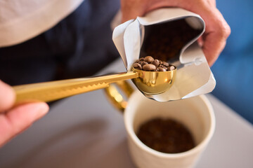 Pouring freshly ground coffee beans into a measuring cup for a perfect morning brew