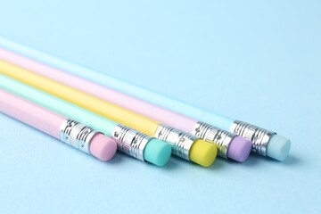 Graphite pencils with erasers on light blue background, closeup