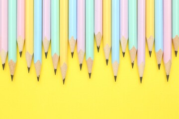Many graphite pencils on yellow background, flat lay. Space for text