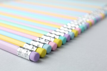 Many graphite pencils with erasers on light grey background, closeup. Space for text