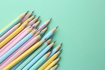 Many graphite pencils on turquoise background, flat lay. Space for text