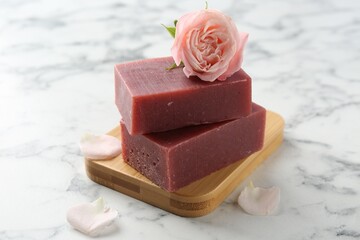 Soap bars and beautiful rose on white marble table, closeup
