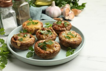 Tasty stuffed mushrooms and spices on white marble table, closeup