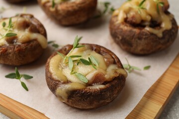 Delicious stuffed mushrooms with melted cheese and thyme on grey table, closeup