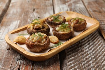 Delicious stuffed mushrooms with melted cheese, garlic and dill on color wooden table, closeup