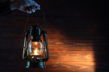 Woman holding vintage kerosene lantern near wooden wall, closeup. Space for text