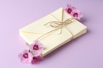 Stack of love letters and carnation flowers on violet background, closeup