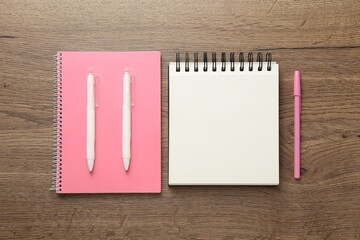 Notebooks and pens on wooden table, flat lay
