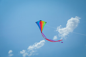 Colorful kite flying in blue sky, low angle view
