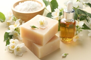 Soap bars, essential oil, sea salt and jasmine flowers on beige background, closeup