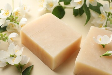 Soap bars and jasmine flowers on beige background, closeup