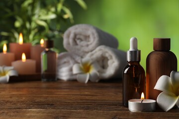 Spa composition with cosmetic products, flowers and burning candles on wooden table against blurred...