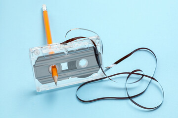 Rewinding audio cassette with pencil on light blue background