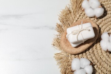 Soap bars and cotton flowers on white marble table, flat lay. Space for text