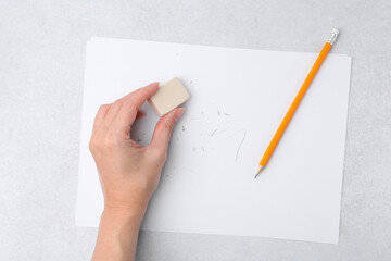 Woman with graphite pencil, eraser and paper sheet at light table, top view