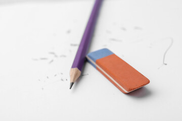 Graphite pencil and eraser on paper sheet, closeup