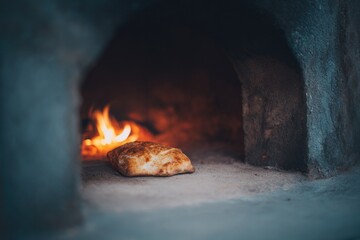 Naklejka premium single piece of bread baking inside tandoor with visible flames highlighting traditional cooking method