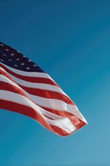 intricately draped american flag gently flutters against clear blue sky