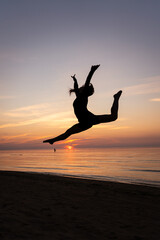 Silhouette of a beautiful woman in a graceful pose against the backdrop of a seascape. A young...