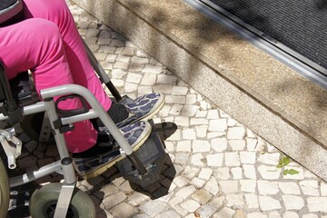 Wheelchair user approaching building entrance with a small step, facing architectural barrier