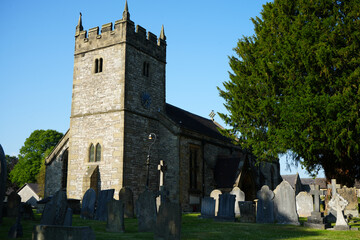 Ashford in the Water, Derbyshire, England - June 20 2025: Old stone church with graveyard at sunset in rural village setting.