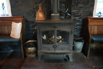 Peak District, England - June 20 2025: Rustic indoor fireplace scene with a wood-burning stove,...