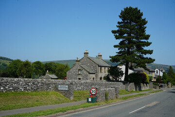 Castleton, Derbyshire, England - June 20 2025: This image captures stone cottages, a village sign,...