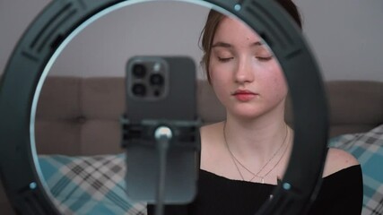 Teenager vlogger making vlog for kids channel. beauty blogging, technology and people concept - happy smiling girl blogger with ring light and smartphone applying make up at home