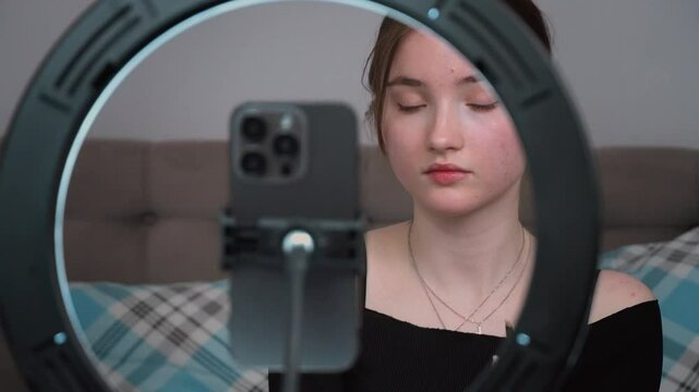 Teenager vlogger making vlog for kids channel. beauty blogging, technology and people concept - happy smiling girl blogger with ring light and smartphone applying make up at home