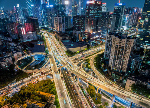 Aerial view of an illuminated multi-level highway interchange with traffic flow amidst modern city buildings at night in Guangzhou.