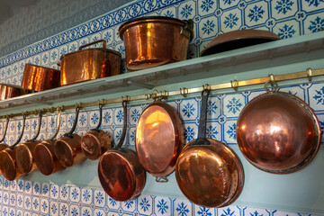 Copper pans lined up on a kitchen wall