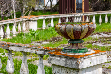 Decaying soviet era planter with dried plants on stone balustrade in garden