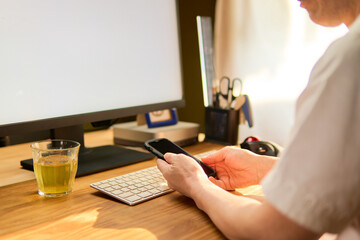 パソコン作業の合間に携帯電話をチェックする50代男性