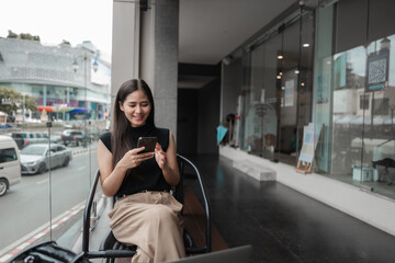Happy businesswoman working remotely using mobile phone while sitting in a cafe