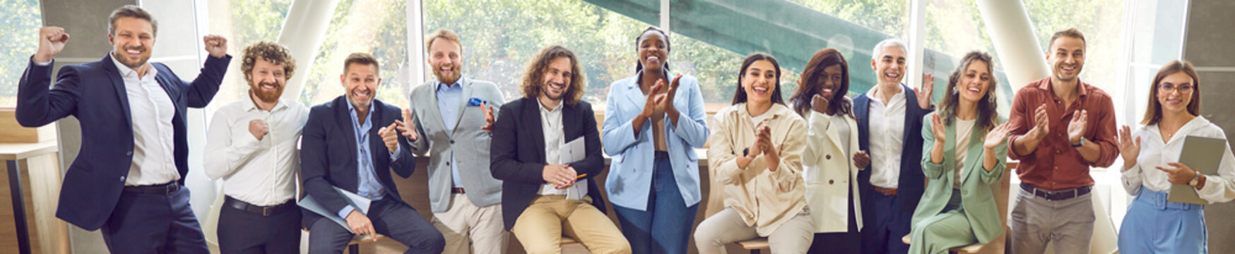 Happy audience applauding after a very good presentation at a business conference. Group of diverse people standing and sitting in a row, clapping hands and smiling. Banner, header. Success concept