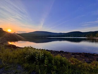 Breathtaking mountain peak at sunset. Stunning scenic view. North South Lake Campground in the Catskill Mountains. Serene summer, dusk. Clear calm blue orange purple sky clouds reflect over lake.