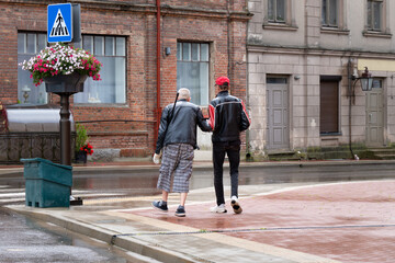 Two Men Walking Together in Small Town After Rain – Support, Friendship and Inclusion in Public...
