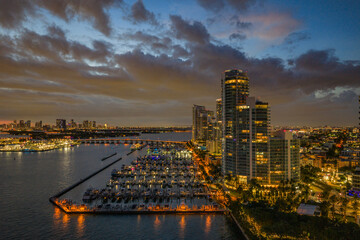 Twilight over Miami skyline and marina. Luxury yachts glowing in the Miami harbor. Sunset cruise near Miami downtown skyscrapers. Aerial night view of Miami Beach at dusk.