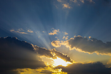 Golden sun rays breaking through clouds in a blue sky create a captivating spectacle, symbolizing...