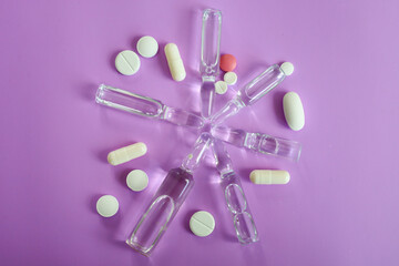 Pharmaceutical preparations and ampoules, arranged in a star shape on a delicate purple background,...