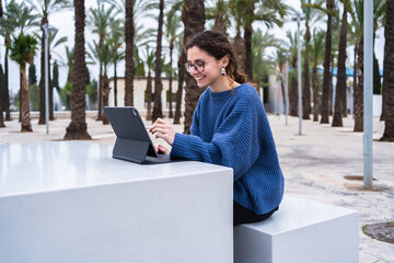 University student using digital tablet and stylus, enjoying outdoor learning in urban park