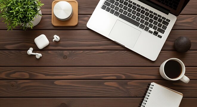Modern workspace arrangement featuring laptop coffee airpods and decorative elements overhead view