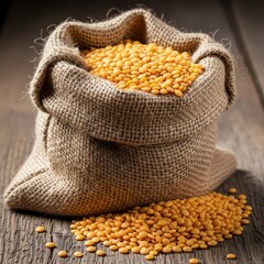 Yellow lentils spilling from a burlap sack on a rustic wooden table