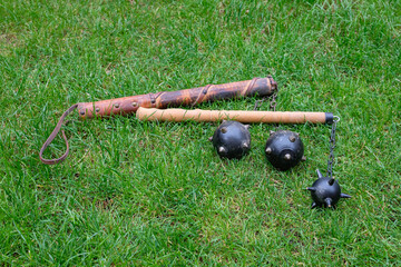 Medieval weapon or Morgenstern mace with spikes lies on green grass. Martial arts and tournaments.