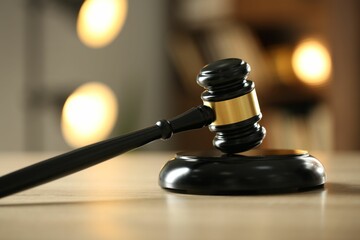 Judge's gavel on wooden table against blurred background, closeup