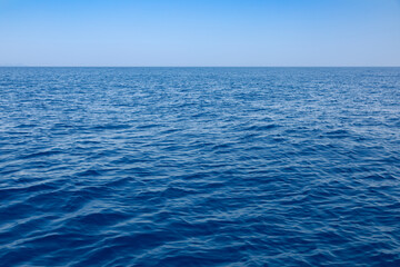 Wide view of calm blue sea surface with horizon in the distance