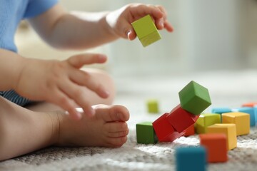 Cute little child playing with colorful cubes at home, closeup